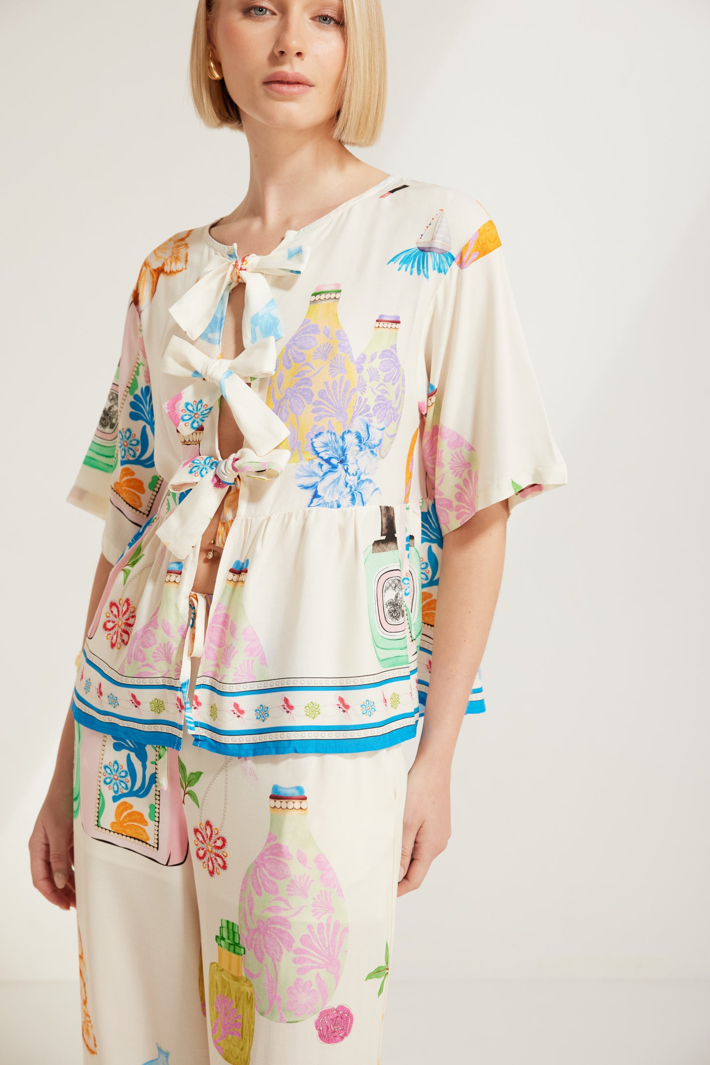 TW4320E Perfume Dreams Tie Front Top in White Print. Australian women’s WHOLESALE SHORT SLEEVE TOPS. This is a Perfume Dreams come in collection with matching sleeveless top, pant, short, jumpsuit, mini dress.